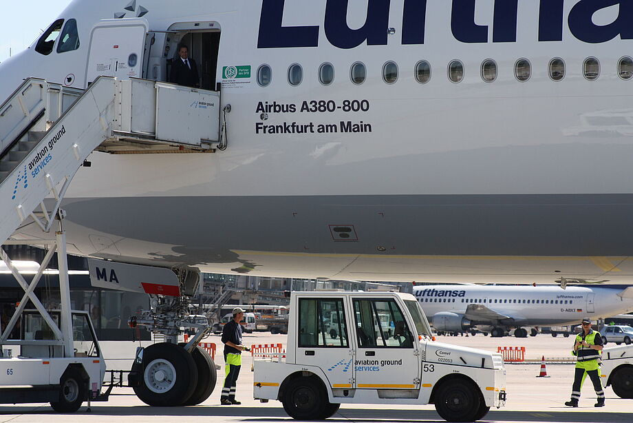 Eine Fluggasttreppe und ein kleiner Schlepper stehen an einem Luftfahrzeug der Lufthansa